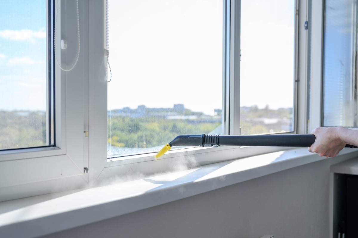 Steam cleaning a window sill and frame detail indoors